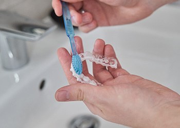 Patient cleaning aligners in sink