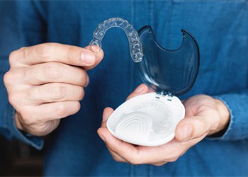 a hand holding a clear aligner 