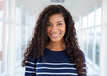 a teenager smiling and standing in a hallway