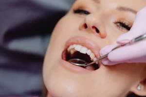 Dentist using dental mirror to examine woman’s teeth