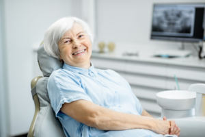 Senior woman smiling while waiting for dentist to whiten her dentures