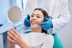 Man checking his smile in the mirror after receiving dental crown in Moses Lake, WA