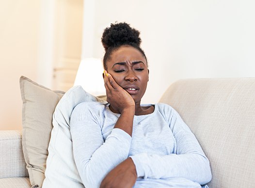 Woman with toothache sitting on couch at home